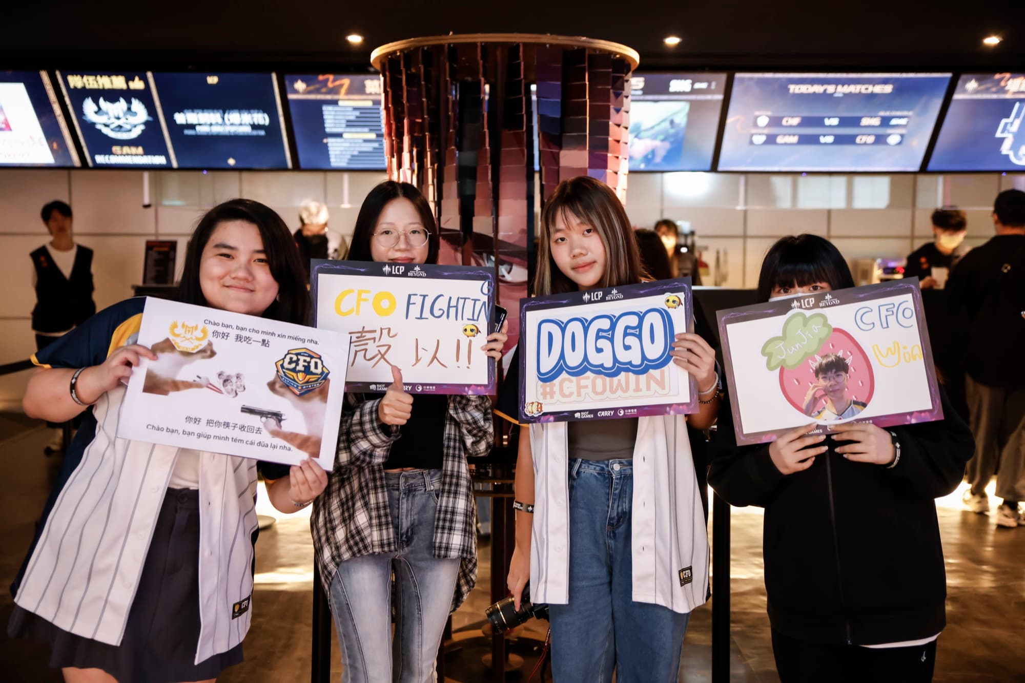 四名粉絲在 LCP 場館大廳持應援牌，TODAY'S MATCHES 賽程板可見