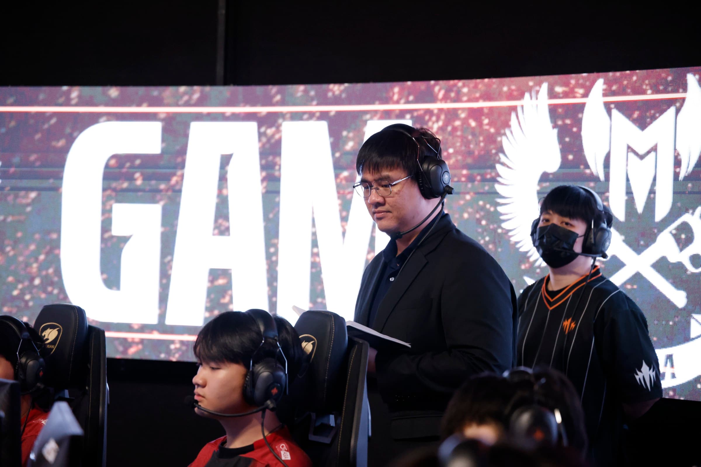 LCP 賽事教練站於選手後方，選手賽中操作中，螢幕顯示 GAME