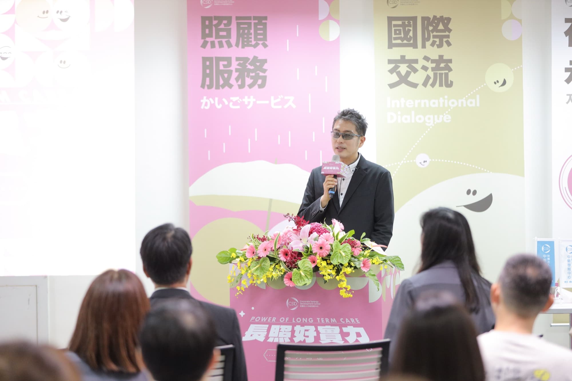 聽眾側面紀錄，多人低頭筆記或側耳聆聽