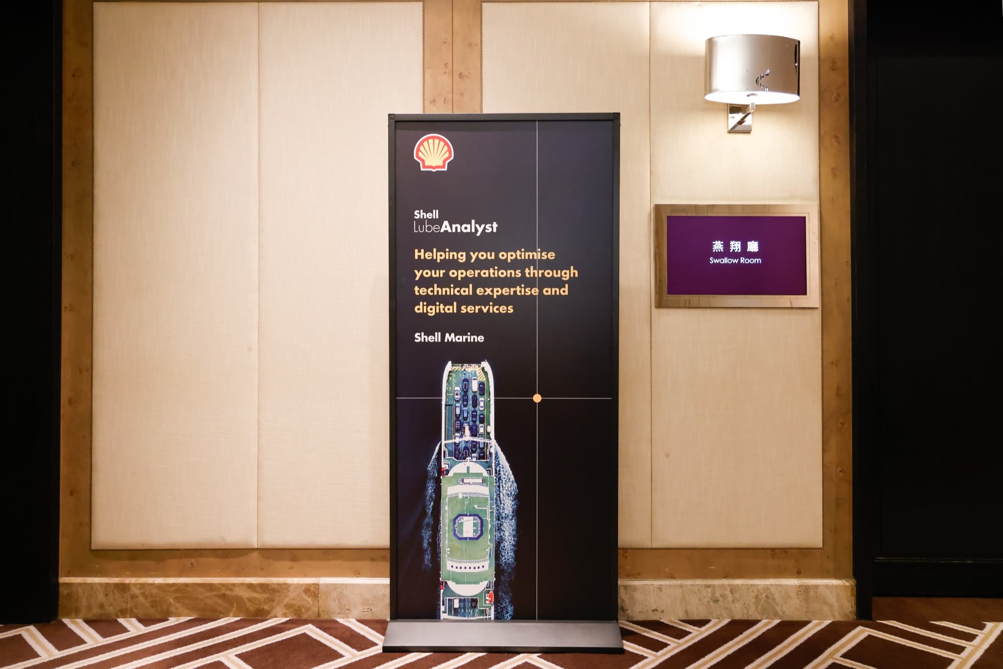 燕翔廳門口的 Shell LubeAnalyst 直立式立牌，印有貝殼標誌、船舶俯瞰圖與 Helping you optimise your operations through technical expertise and digital services 標語