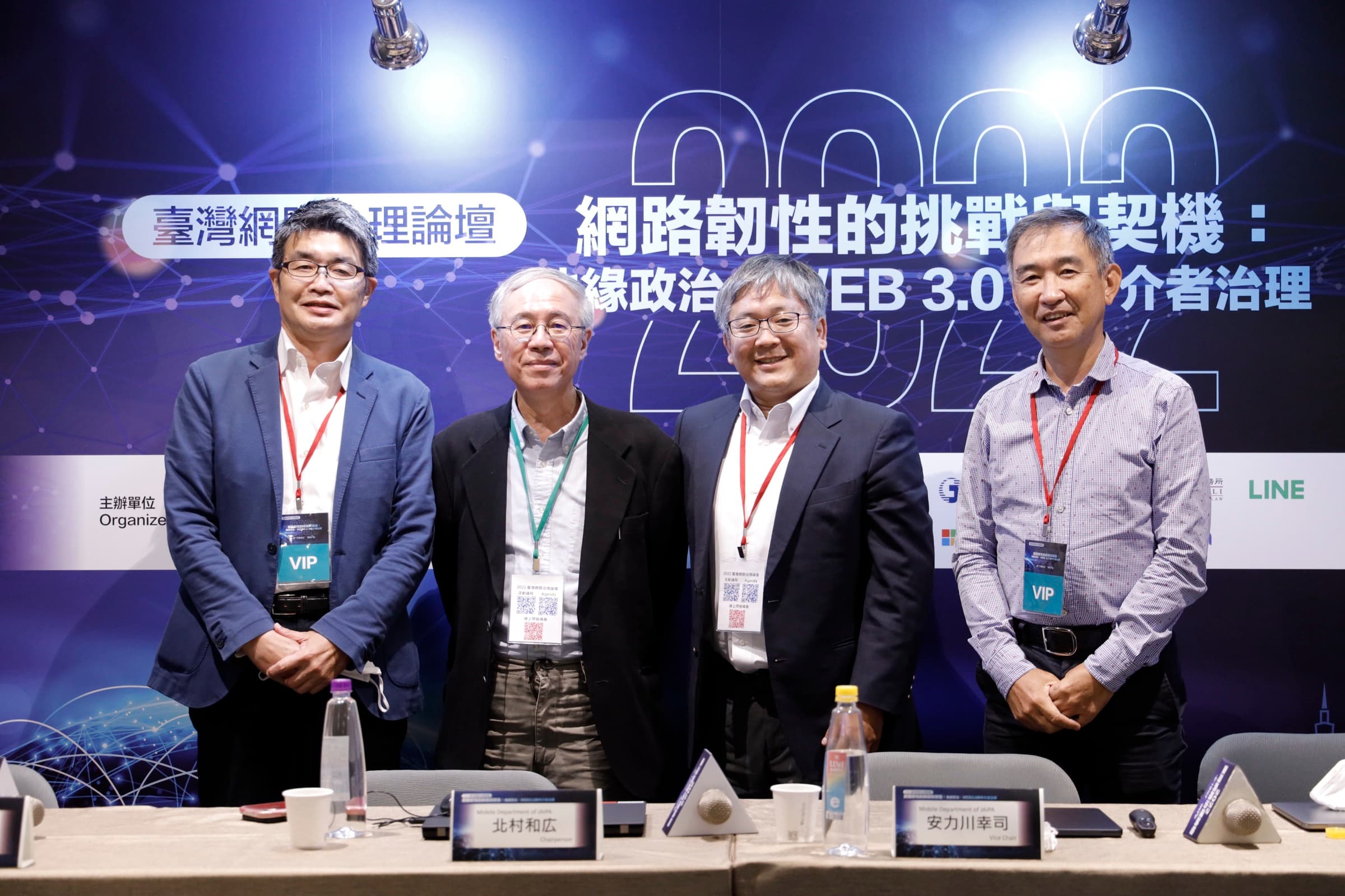 四位與談嘉賓（含配戴 VIP 證的海外代表）於論壇主視覺前並肩合影