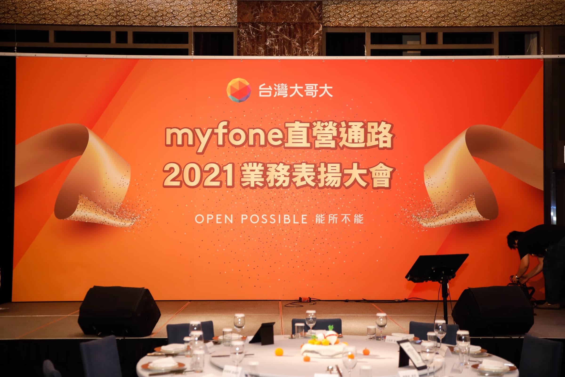 『台灣大哥大 myfone 直營通路 2021 業務表揚大會 OPEN POSSIBLE 能所不能』的橘色舞台背板，前方為空的舞台