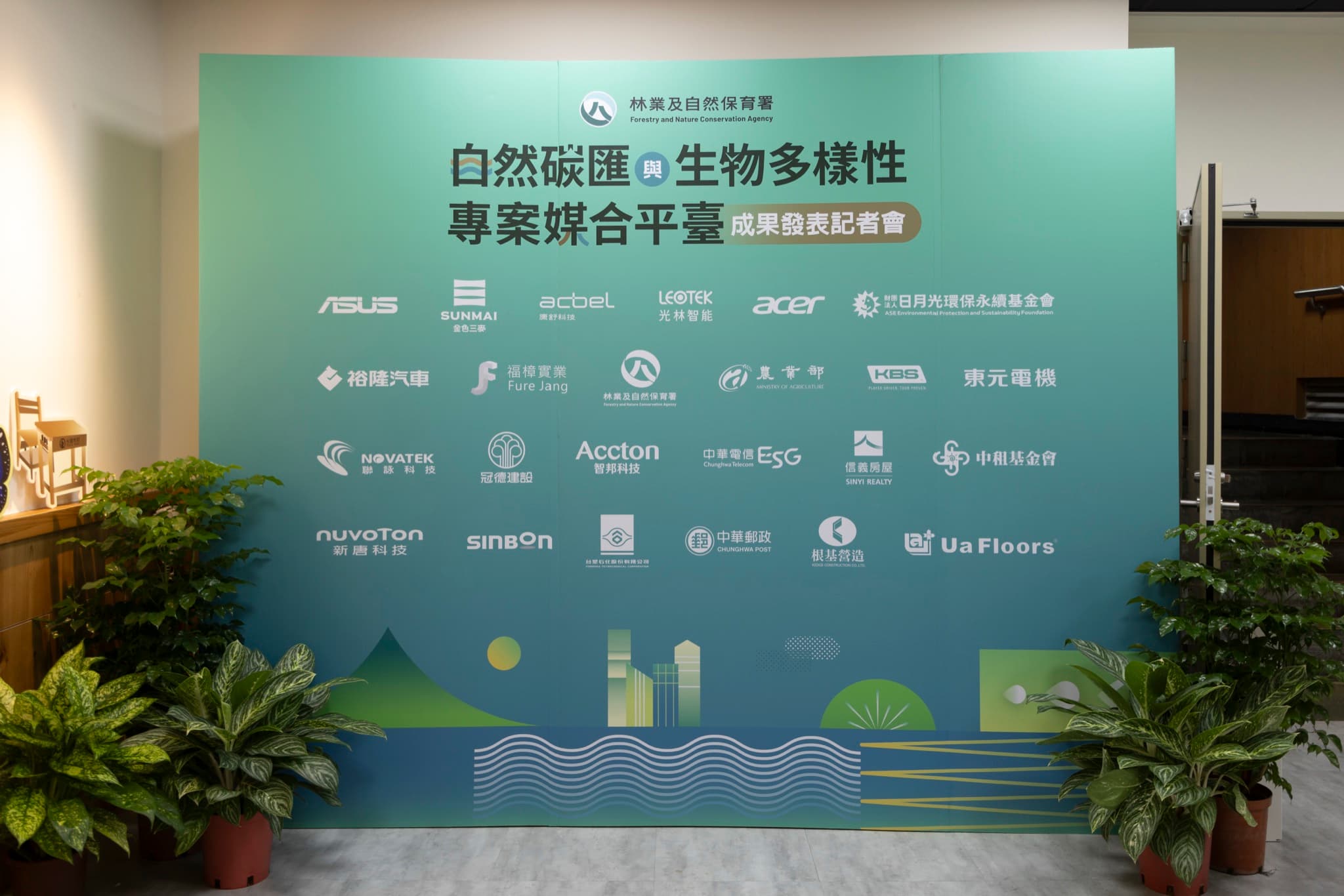 活動主視覺背板全景,印有林業及自然保育署署徽、記者會名稱與二十多家參與企業標誌,背板兩側擺放綠色盆栽。