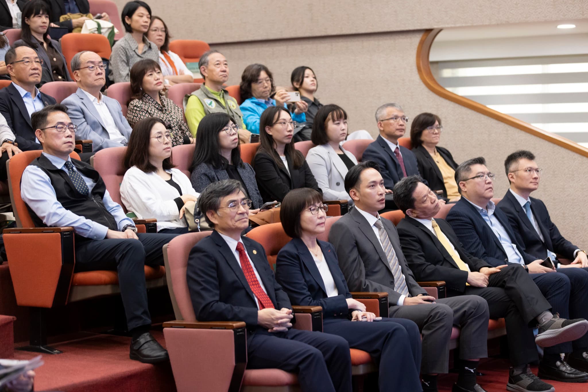 企業代表與貴賓於觀眾席就座聆聽,前排多位西裝與套裝出席者神情專注。