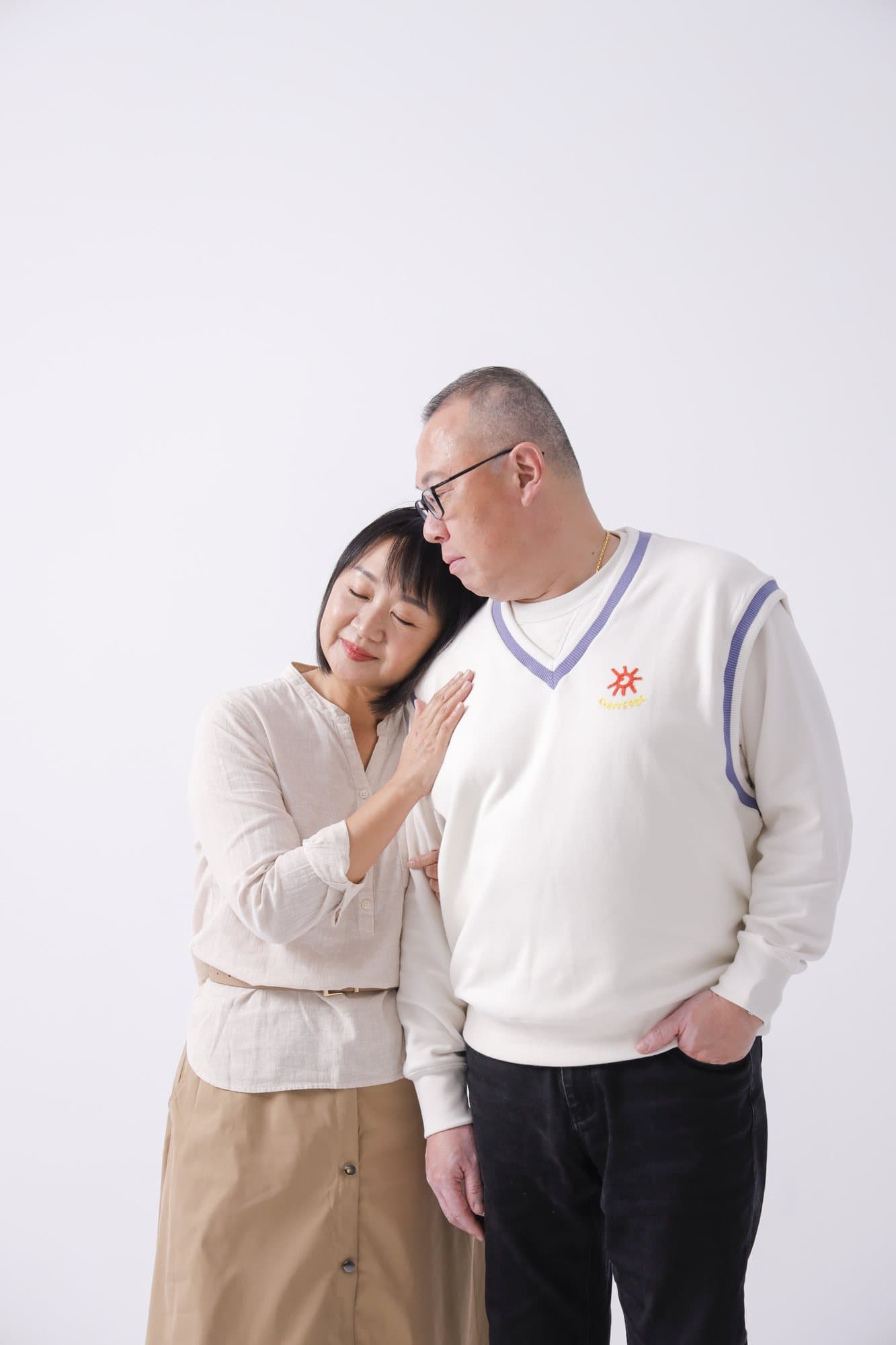 女子側頭依偎在男子肩上的白棚雙人像