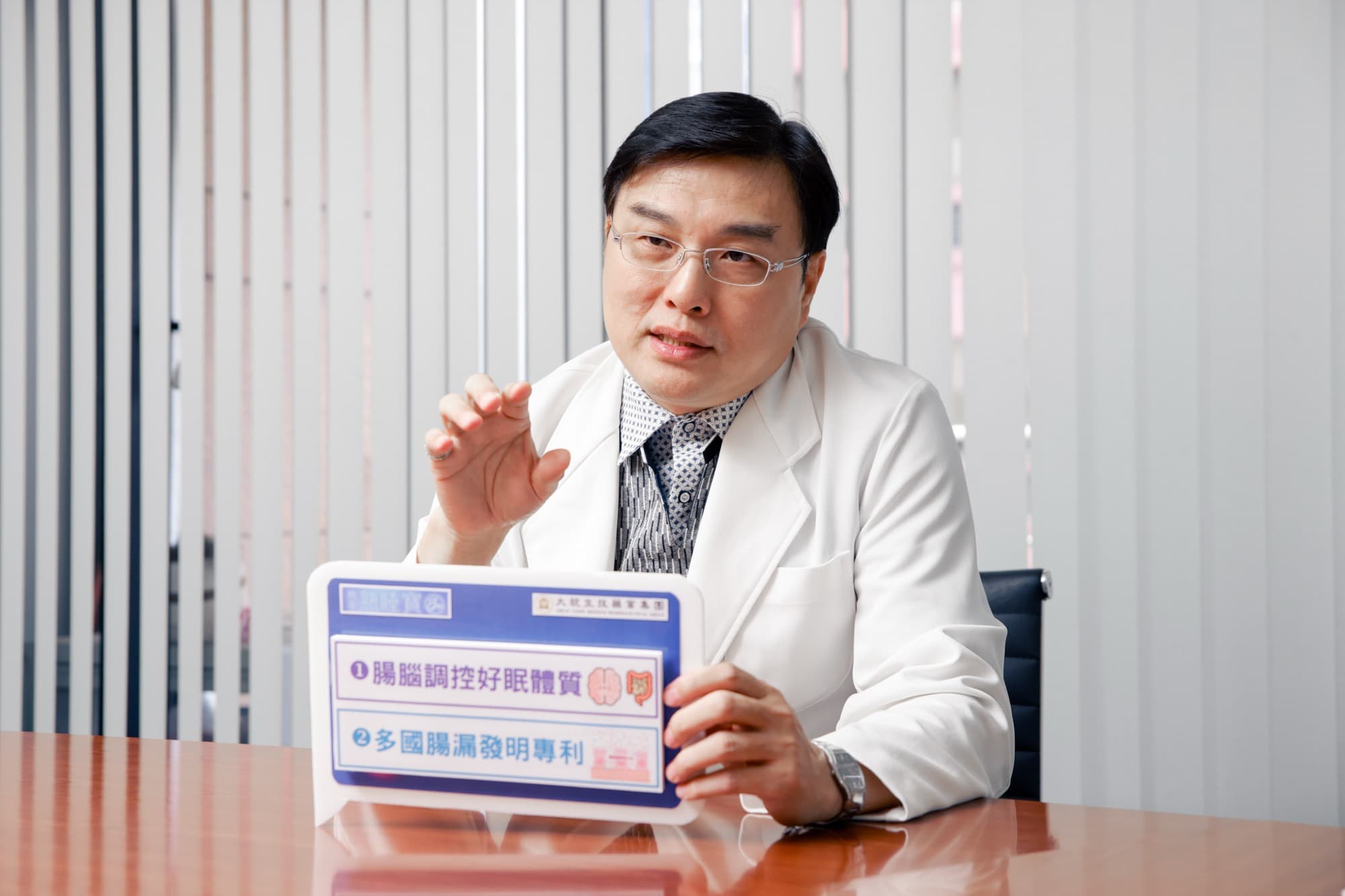 醫師受訪時手持腸腦軸衛教圖卡解說的側拍