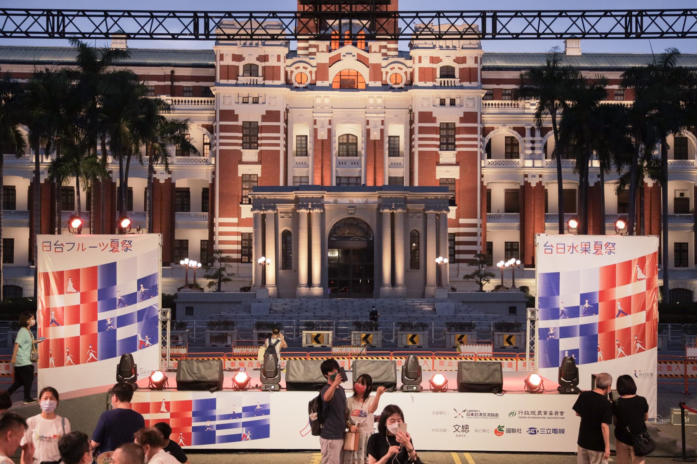 夜間打光的總統府前,台日水果夏祭舞台兩側立起紅白藍配色的『台日水果夏祭/日台フルーツ夏祭』大型布幔,舞台裙印有主辦單位識別