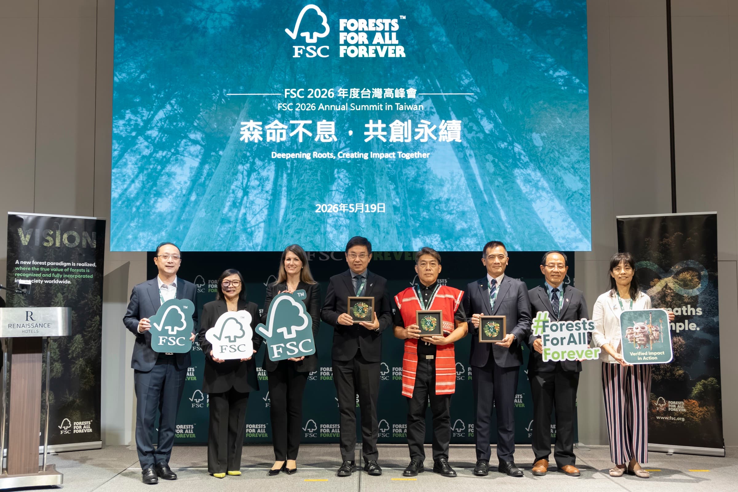 八位貴賓於舞台持 FSC 標章手板與 Forests For All Forever 手牌合影,含原住民族代表