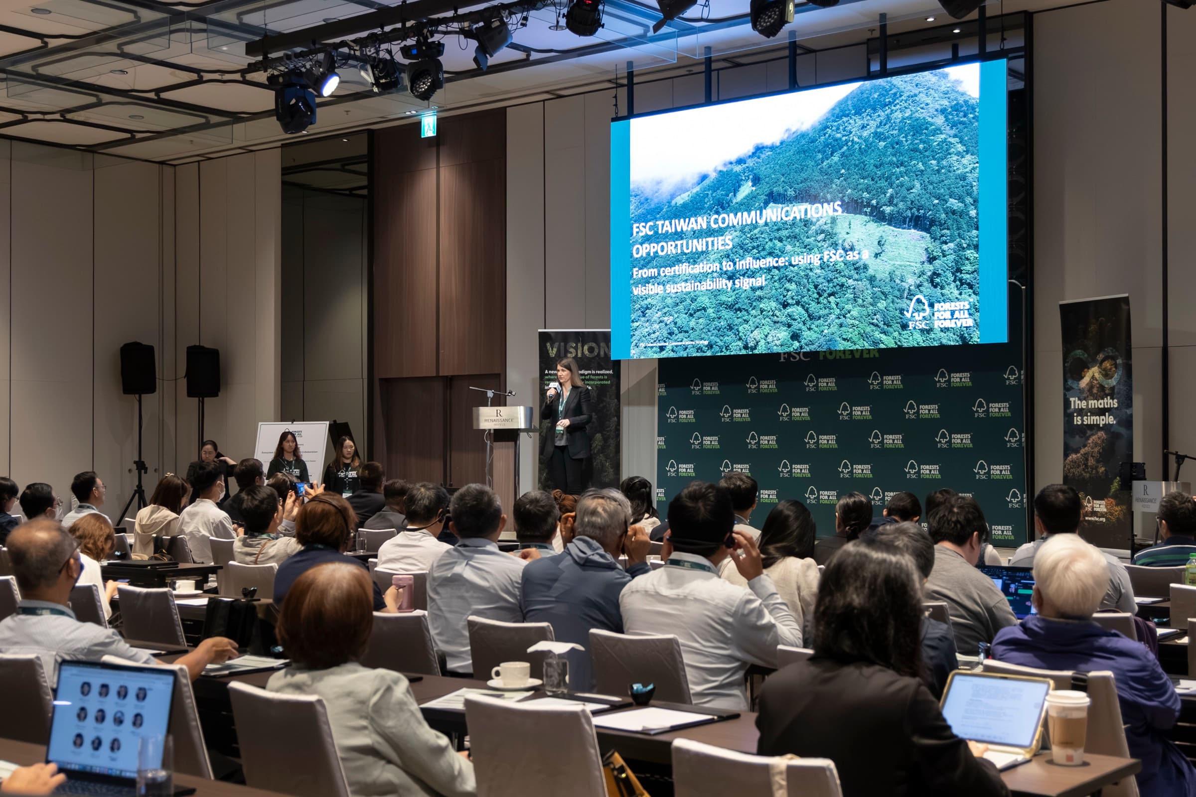 國際講者於舞台演講,大螢幕標題 FSC Taiwan Communications Opportunities,台下全場聽眾專注聆聽
