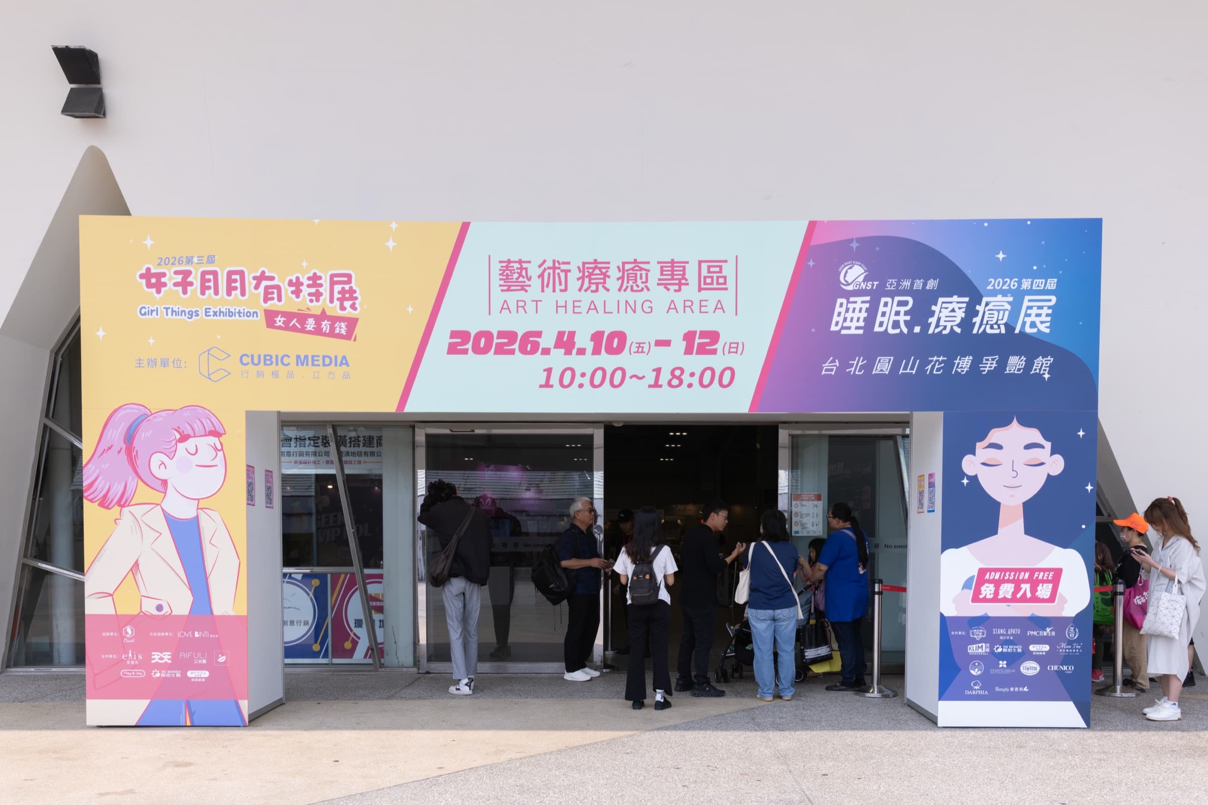 台北圓山花博爭艷館入口大型看板,並列標示第三屆女子月月有特展(Girl Things Exhibition・女人要有錢)、藝術療癒專區與第四屆睡眠療癒展,註明 2026.4.10–12、免費入場、主辦立方品,民眾陸續進場
