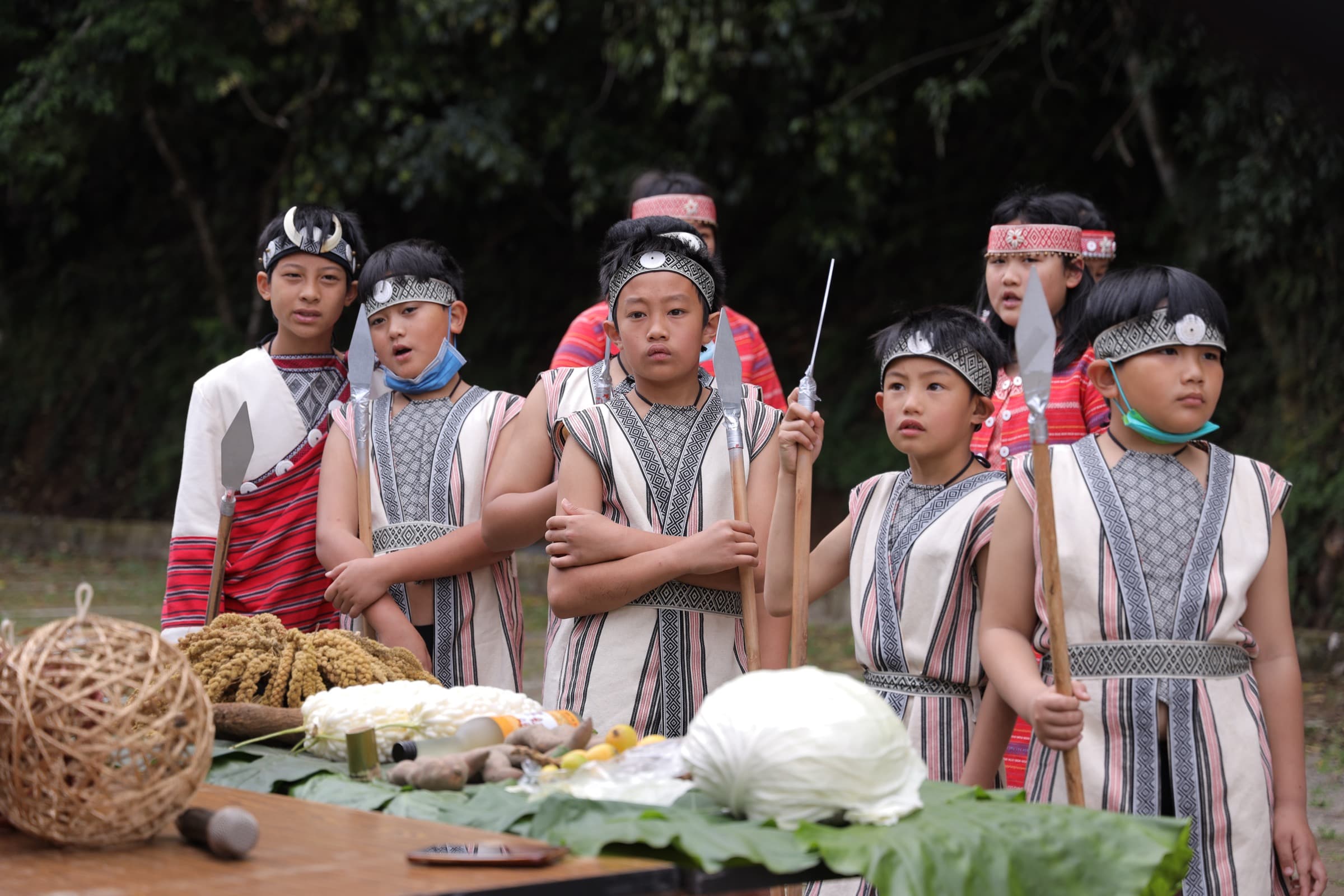 原民少年持杖於祭品桌前列站