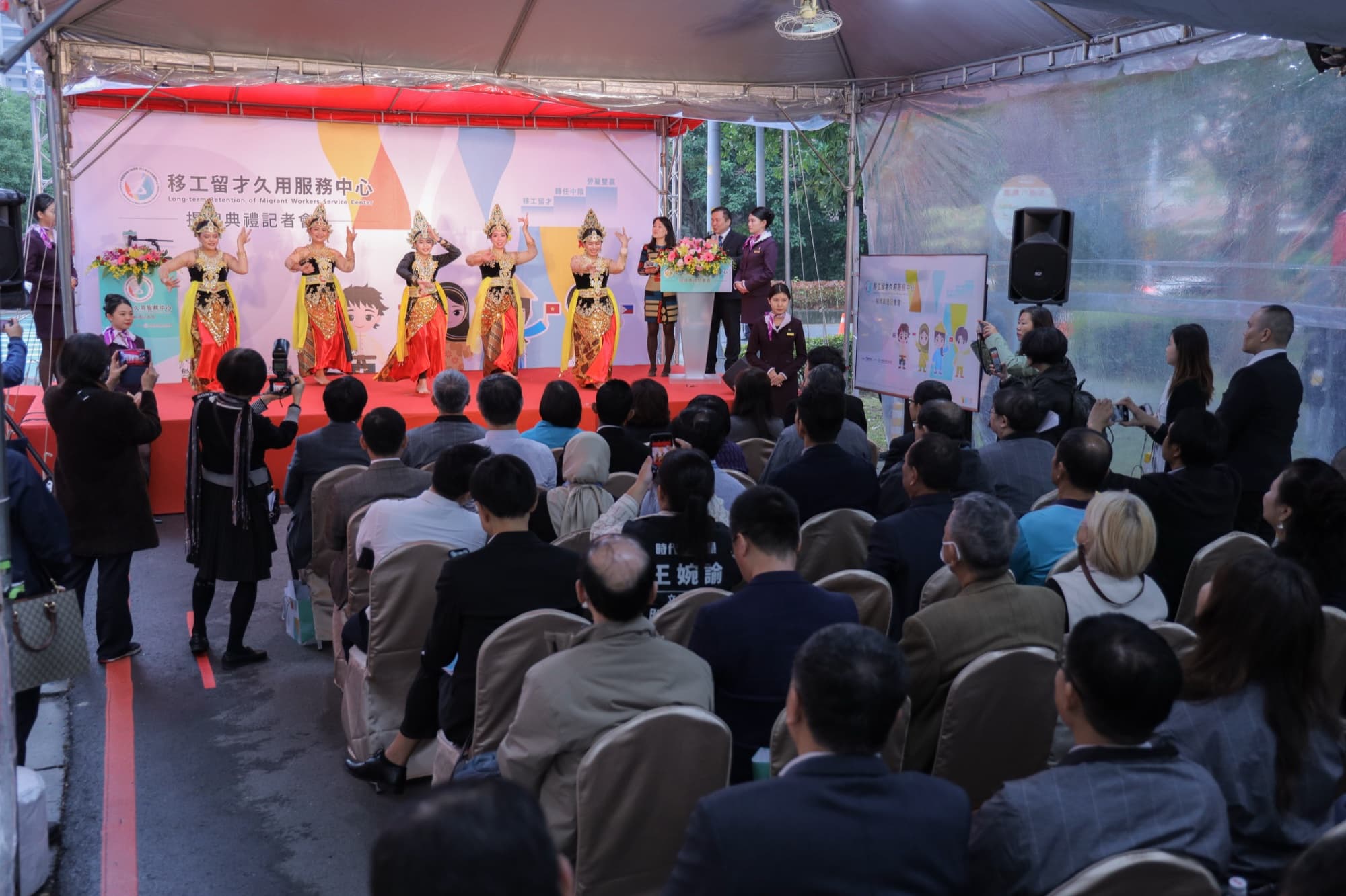 致詞代表手持麥克風站於發言台,背景橫幅清晰