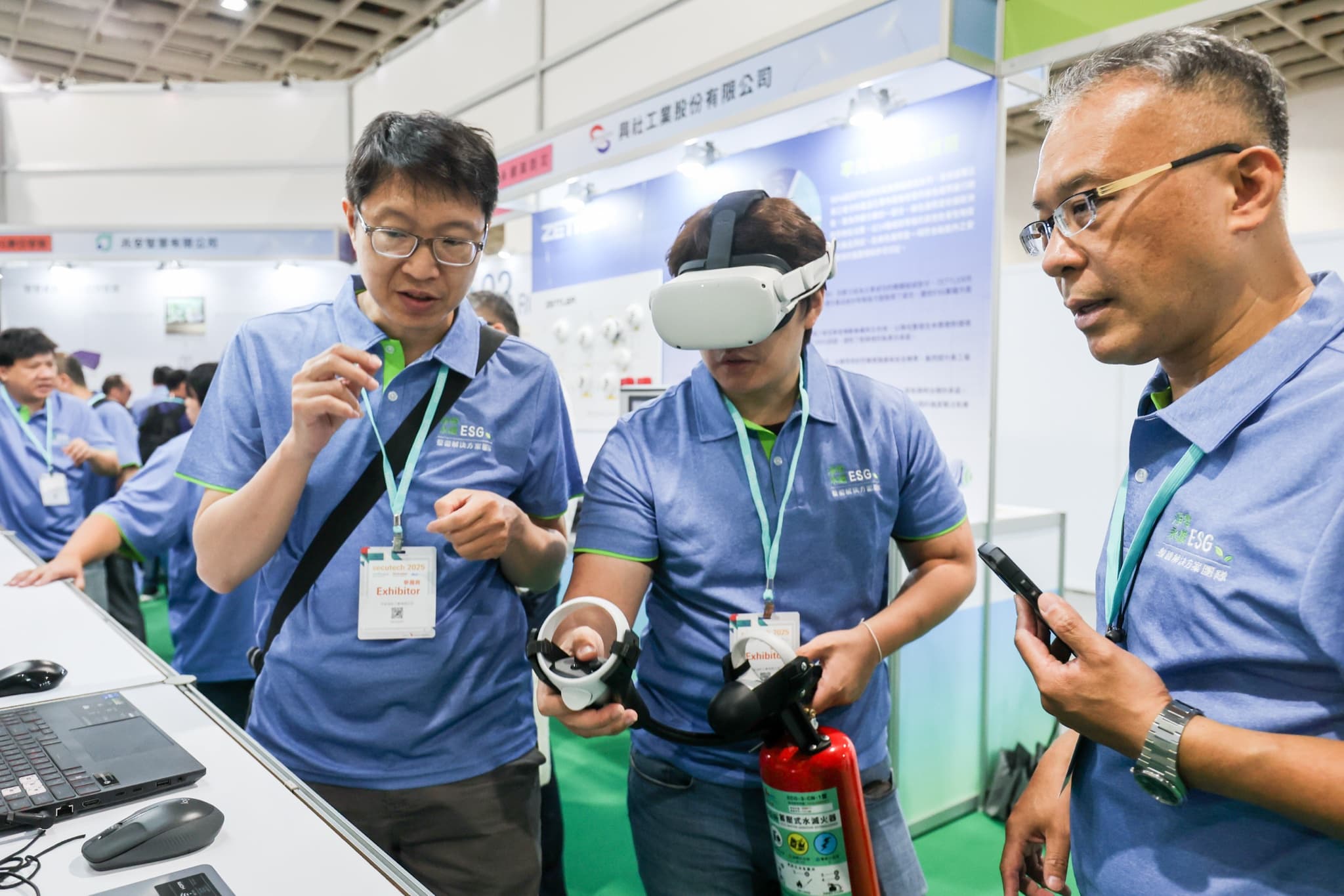 戴VR頭盔的體驗者手持滅火器控制器,兩名配戴secutech 2025參展證的人員在旁引導