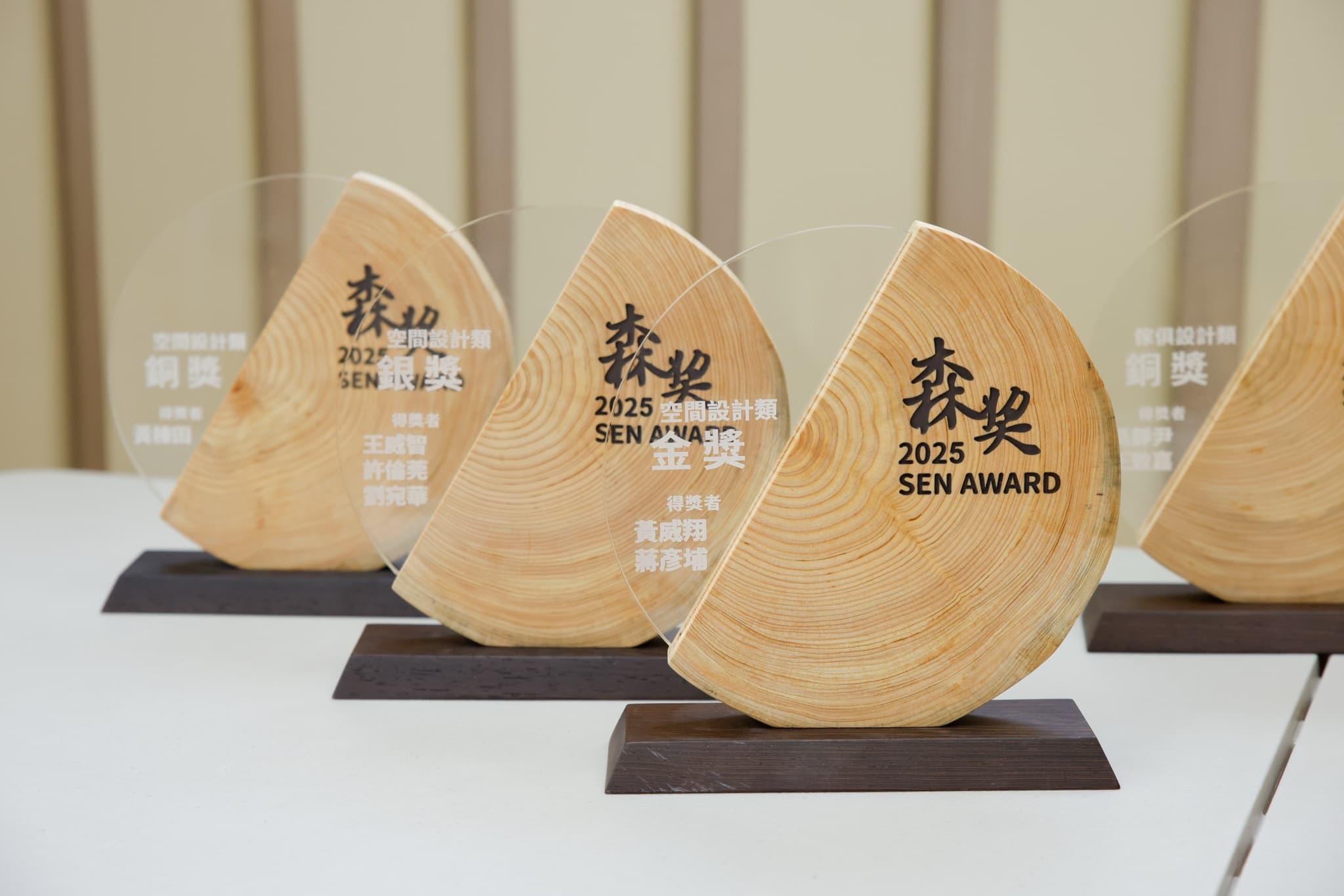 一排木質年輪造型獎座排列桌上,刻有森獎2025 SEN AWARD與得獎者姓名