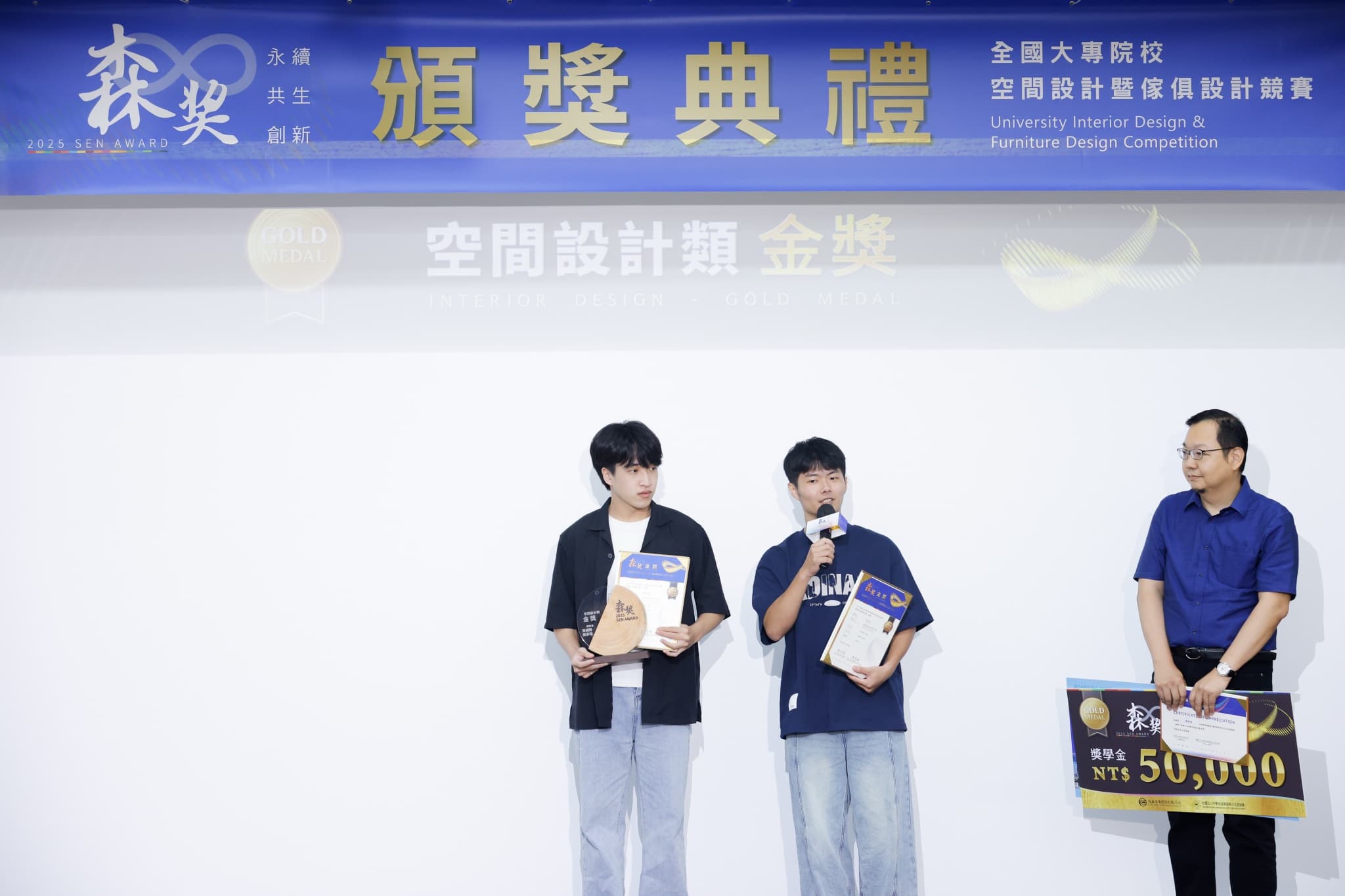 空間設計類金獎兩位學生得獎者於台上發表感言,頒獎人持NT$50,000獎學金大支票,布幕標示空間設計類金獎