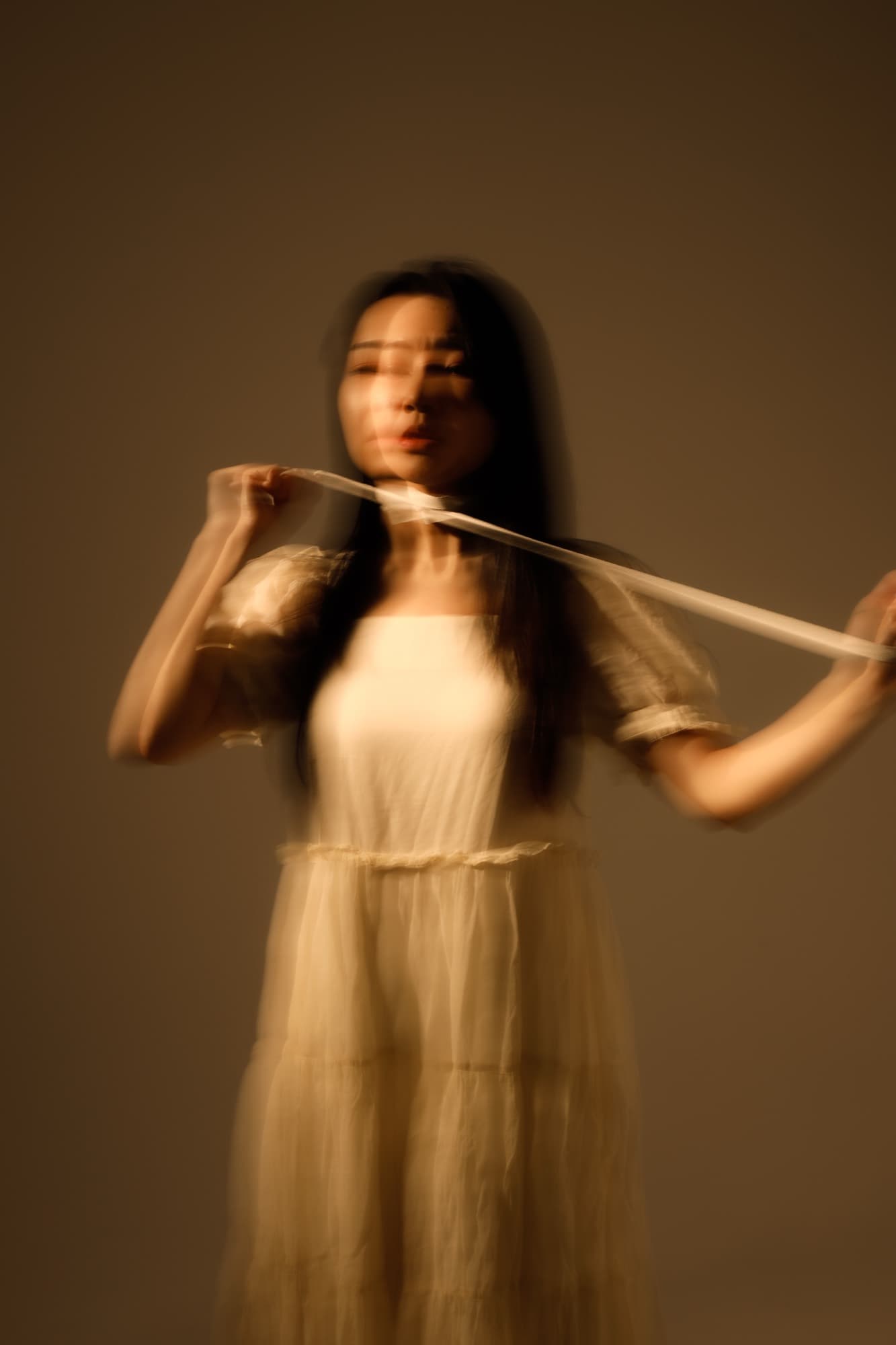 米白洋裝女子拉開緞帶,動態模糊營造的朦朧人像