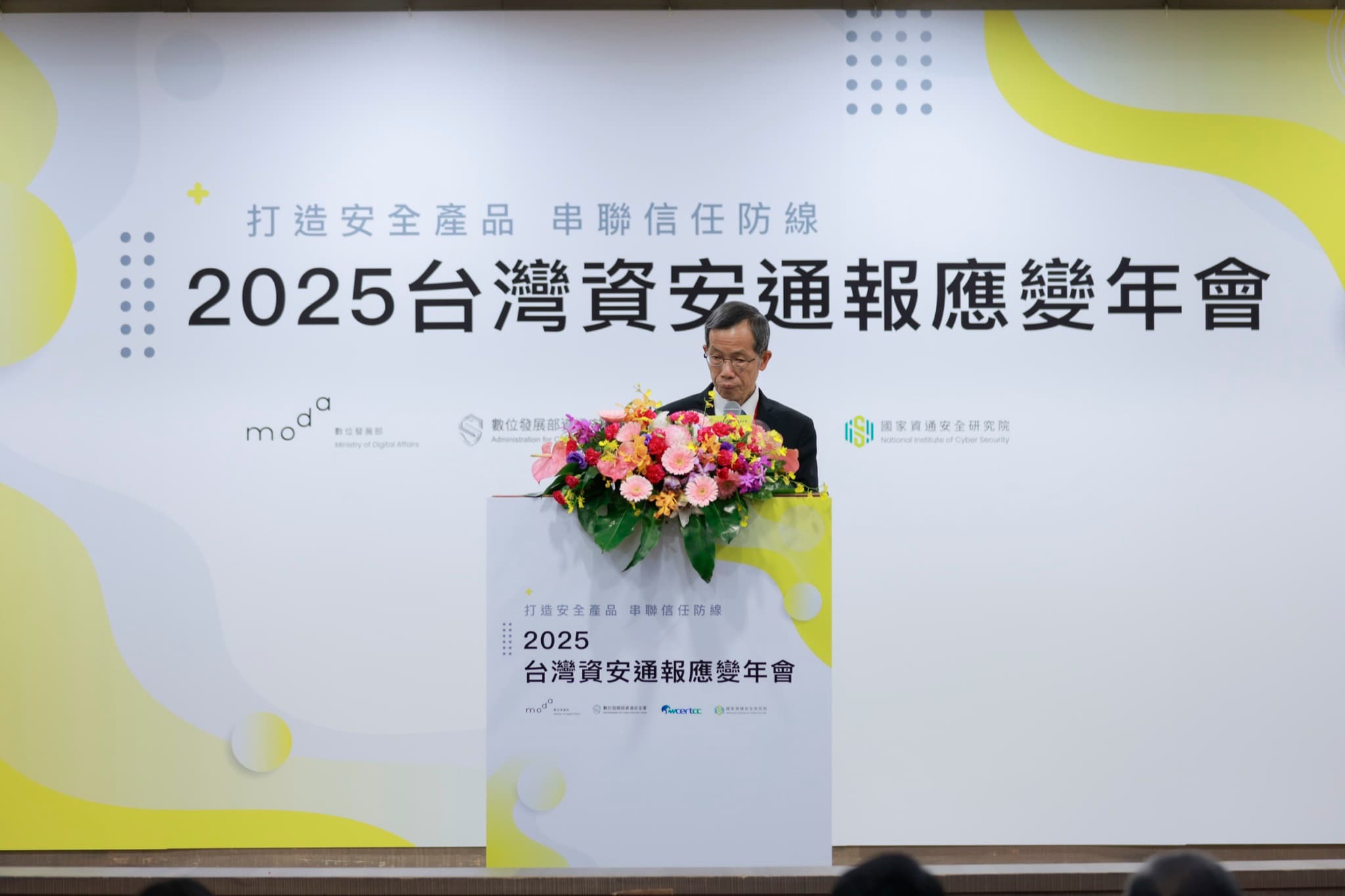 長官於講台開幕致詞,背板印年會名稱與moda、資通安全署、資安院標誌