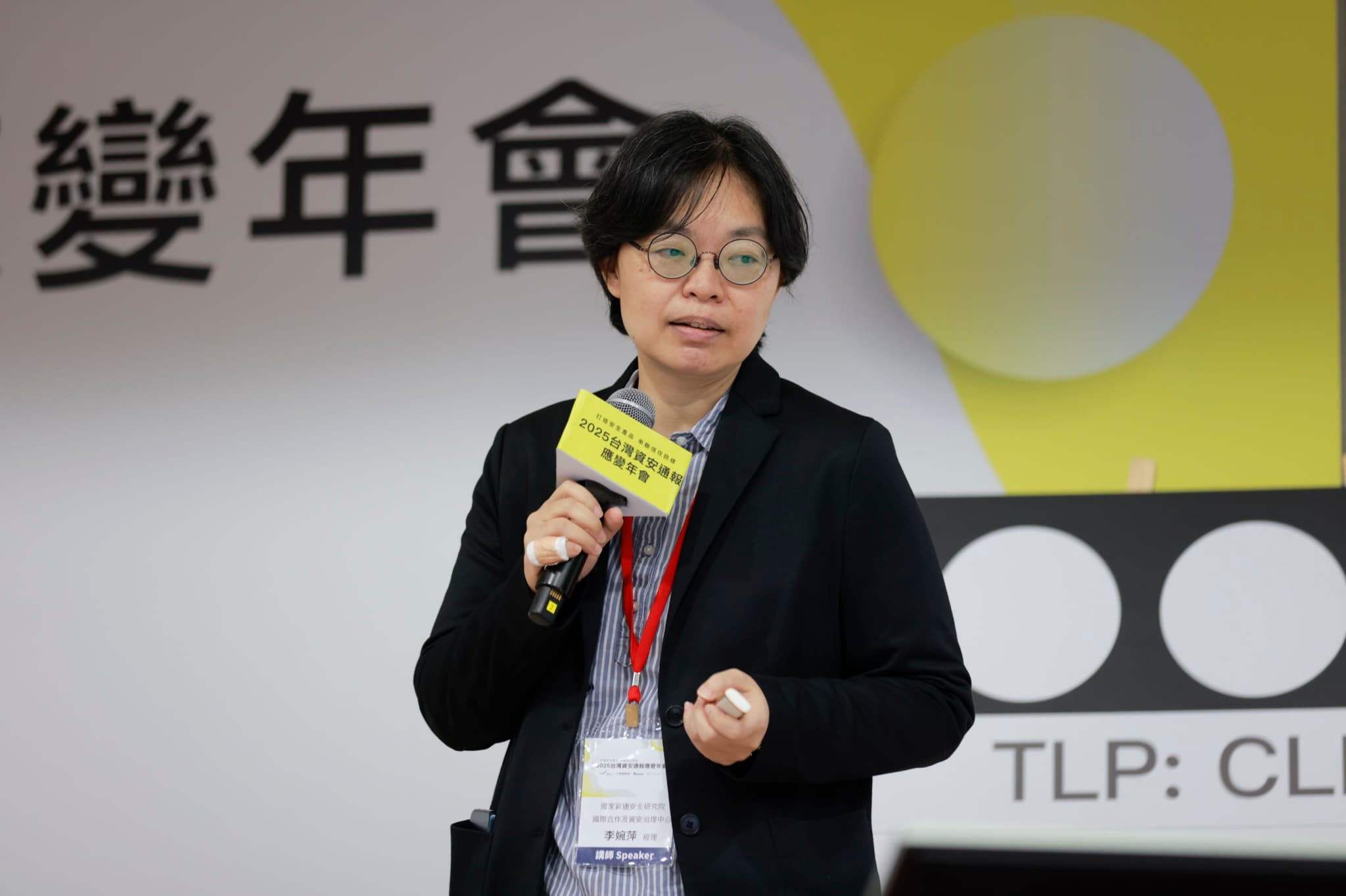 資安院講師手持年會麥克風牌說明,後方簡報顯示TLP分級字樣