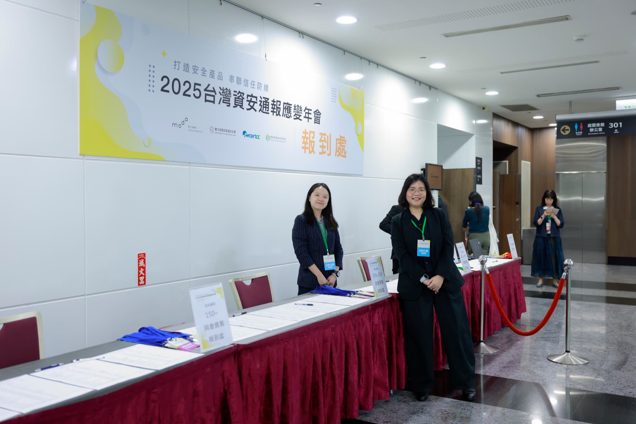 報到處長桌與工作人員,背板印2025台灣資安通報應變年會報到處及主辦單位logo